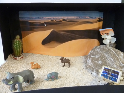 Wir haben in unser Objekt einen echten Kaktus gepflanzt, typische W�stenbewohner werden als Plastiktiere dargestell. Die Fotovoltaikplatte zeigt die Stromversorgung in der W�ste und der Propeller, dass viele St�rme in der W�ste sind.